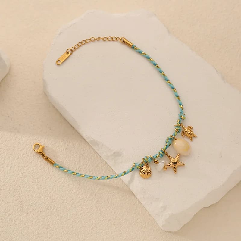 Pulsera con dijes de estrella de mar y concha sobre cadena de cordón